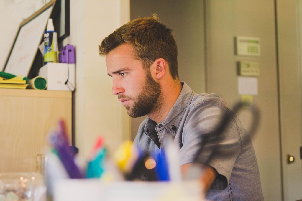 Un homme assis à son bureau avec un expression concentré, dans un décor travail.