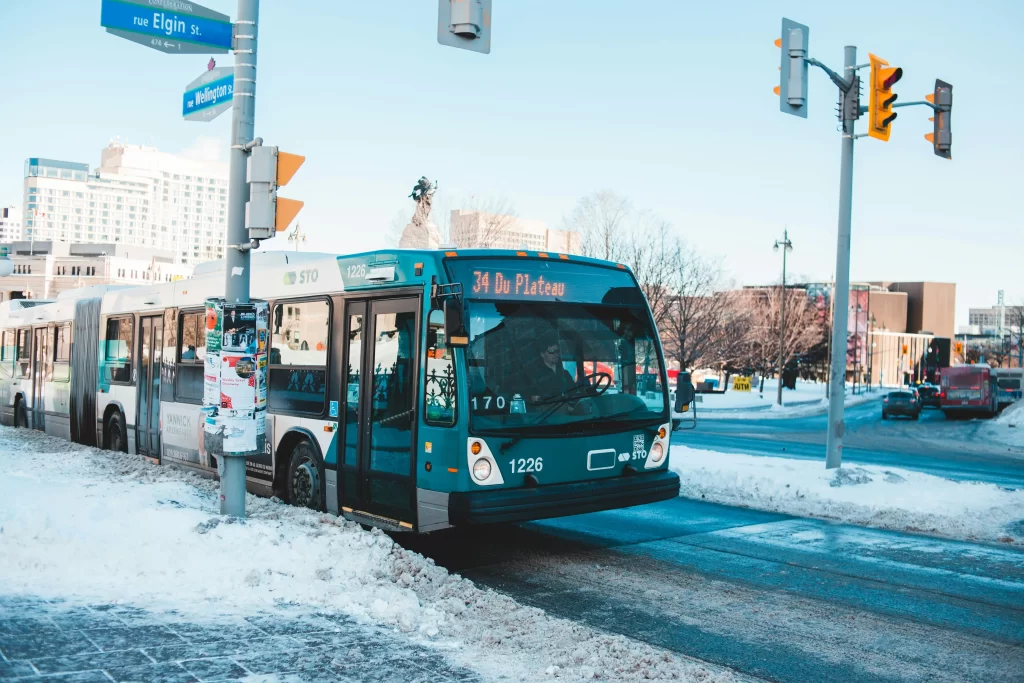 Autobus urbain de la STO en service hivernal à un carrefour routier enneigé en ville.