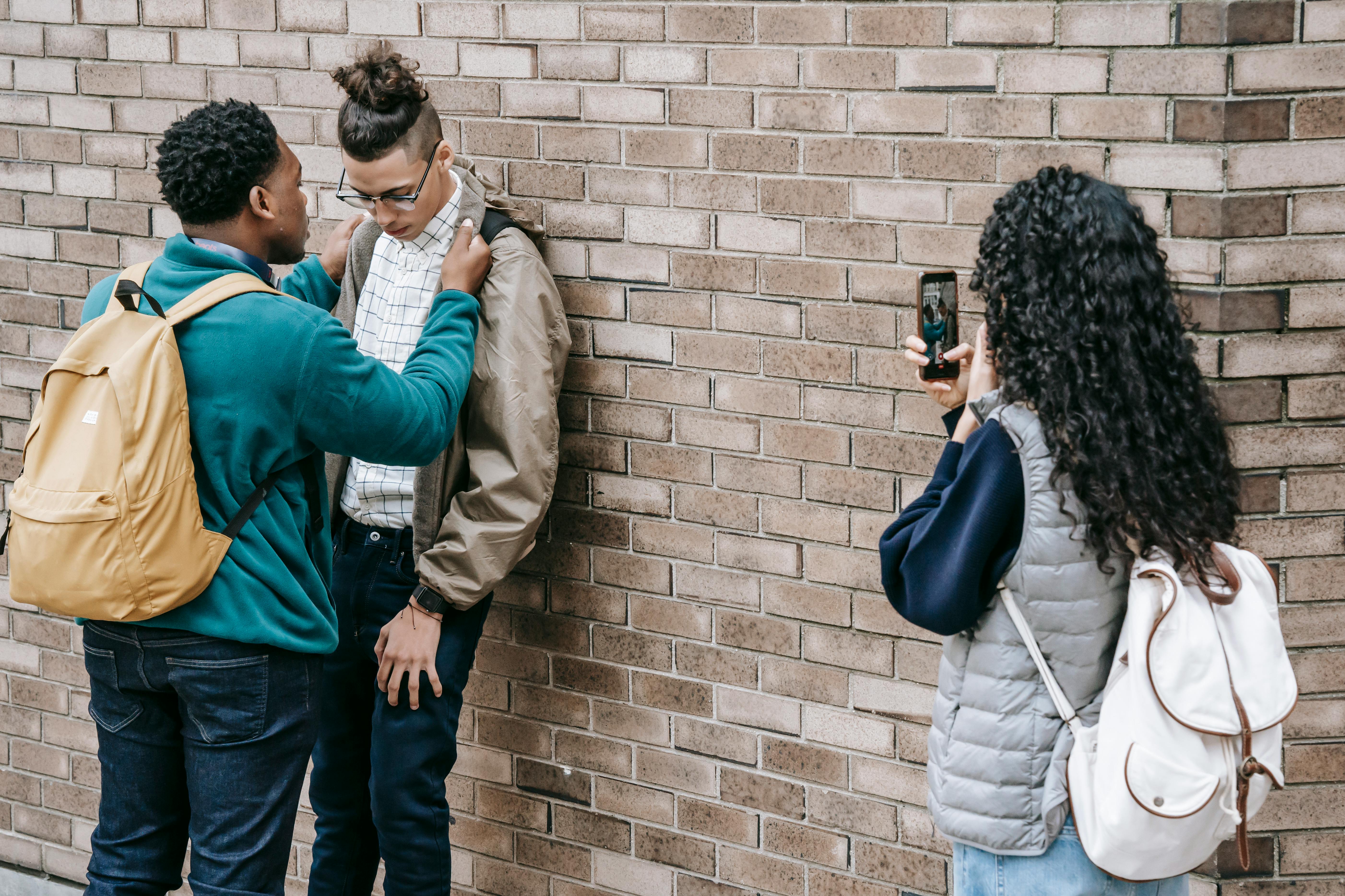 Une personne qui intimide un victime et un spectateur qui enregistre sur son cellulaire.